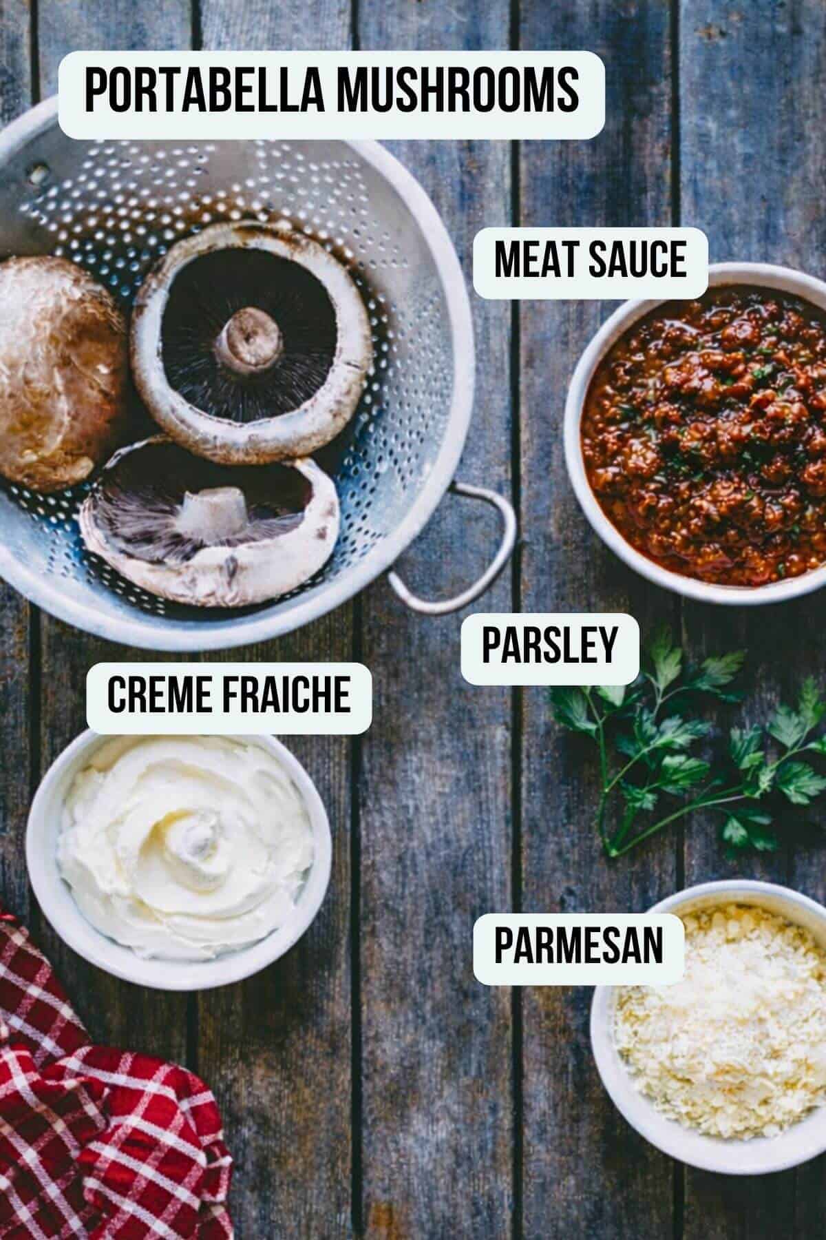 Ground beef stuffed mushrooms ingredients including portobello mushrooms, meat sauce, crème fraîche, parsley and grated parmesan on rustic wooden table.