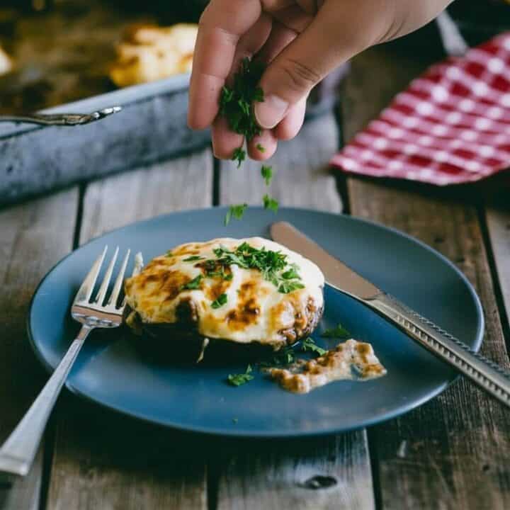 mushrooms stuffed with beef and cheese being sprinkled with freshly chopped parsley.