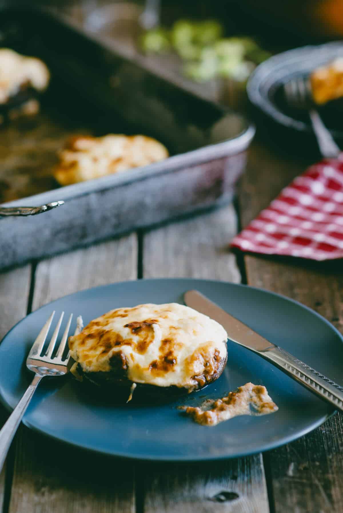 Ground beef stuffed portobello mushroom topped with melted cheese served on a blue plate.