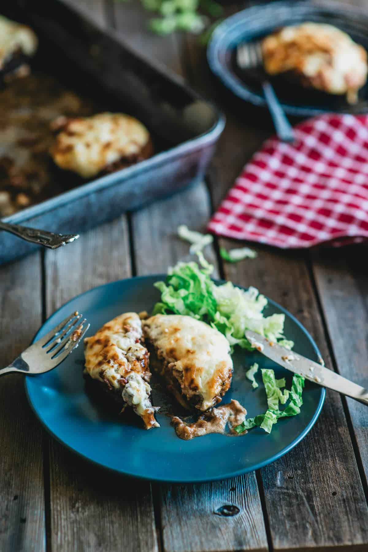 Stuffed portobello mushrooms with ground beef filling and melted cheese served with salad.