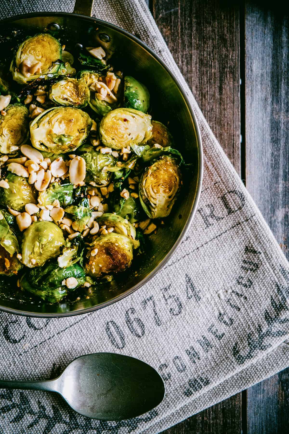 Detailed overhead view of roasted Brussels sprouts with honey glaze and chopped peanuts.