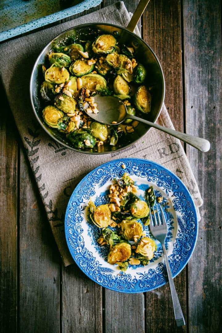 Roasted Brussels sprouts with honey and peanuts served on a blue plate.