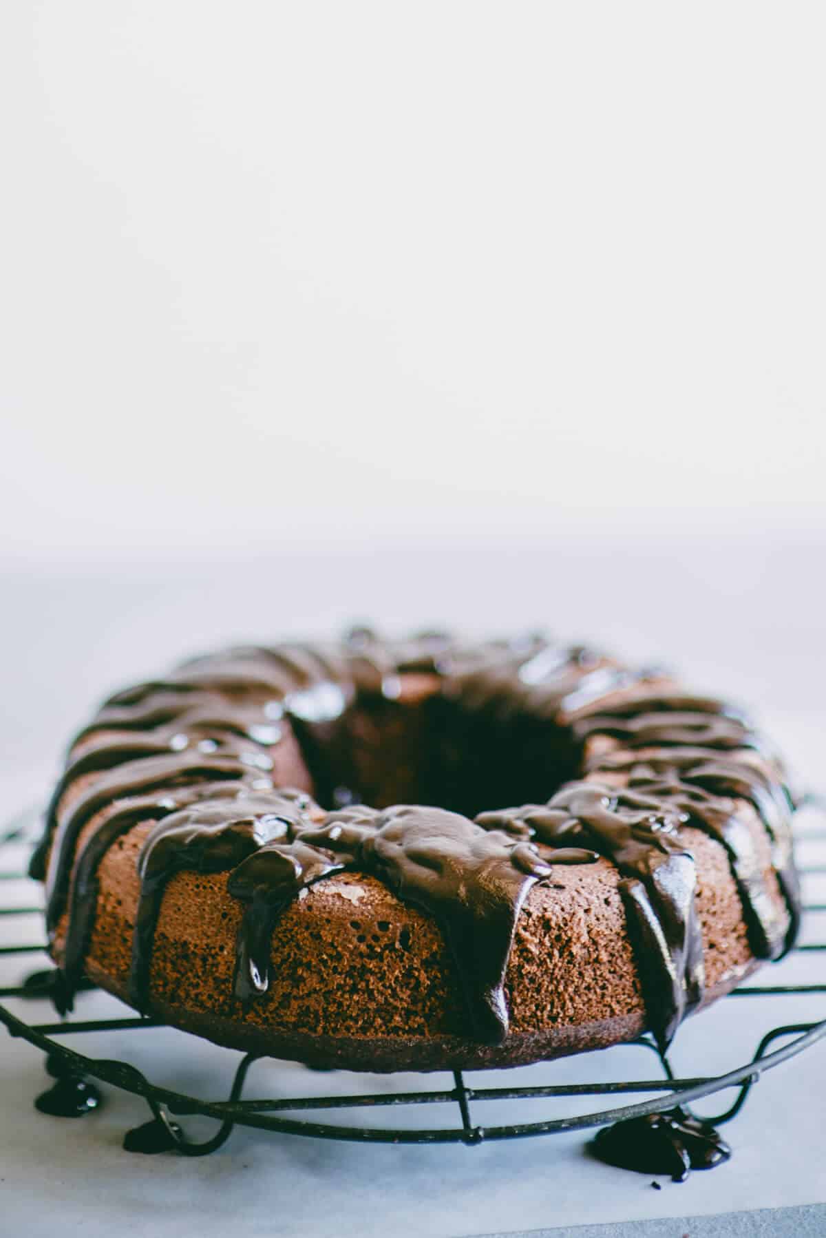 Chocolate beetroot cake cooling on a rack with dark chocolate ganache dripping over the top.