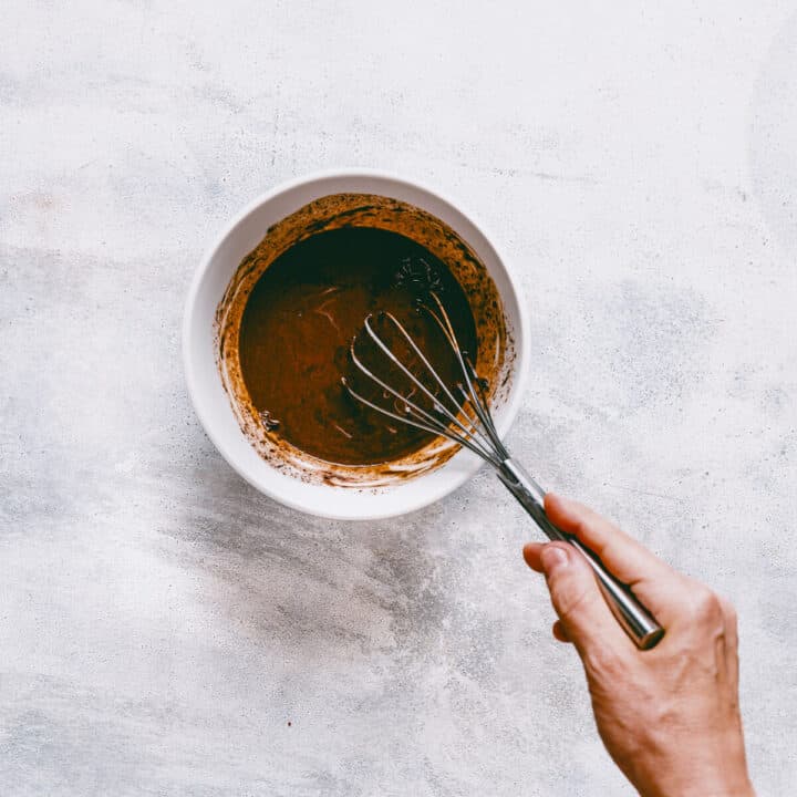 Smooth dark chocolate ganache in a bowl ready to pour over cake.