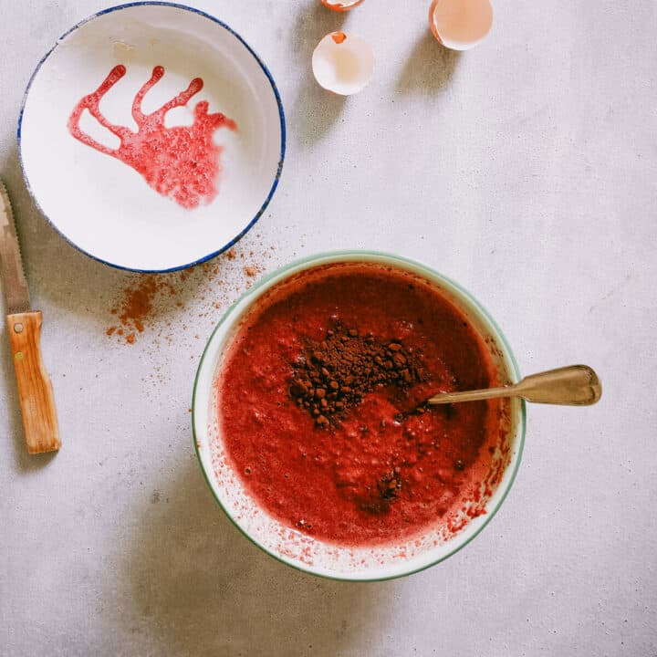 Chocolate and beetroot cake batter being mixed in a bowl with cacao added on top.
