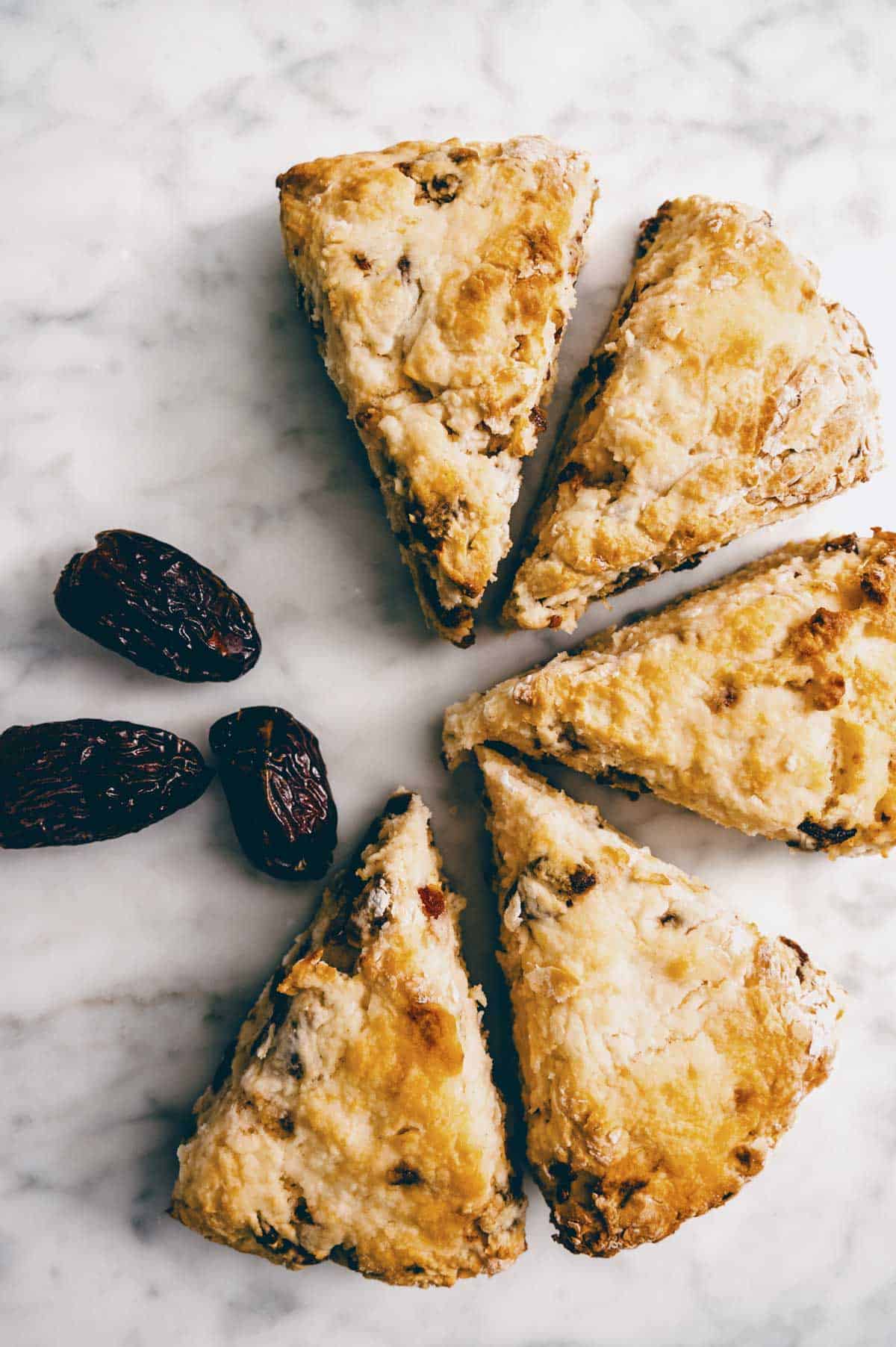 baked date scones with whole medjool dates on marble surface.
