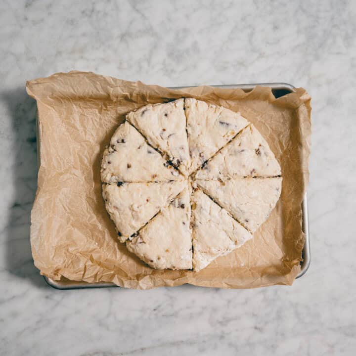 scone dough shaped into circle and cut into wedges on baking tray.