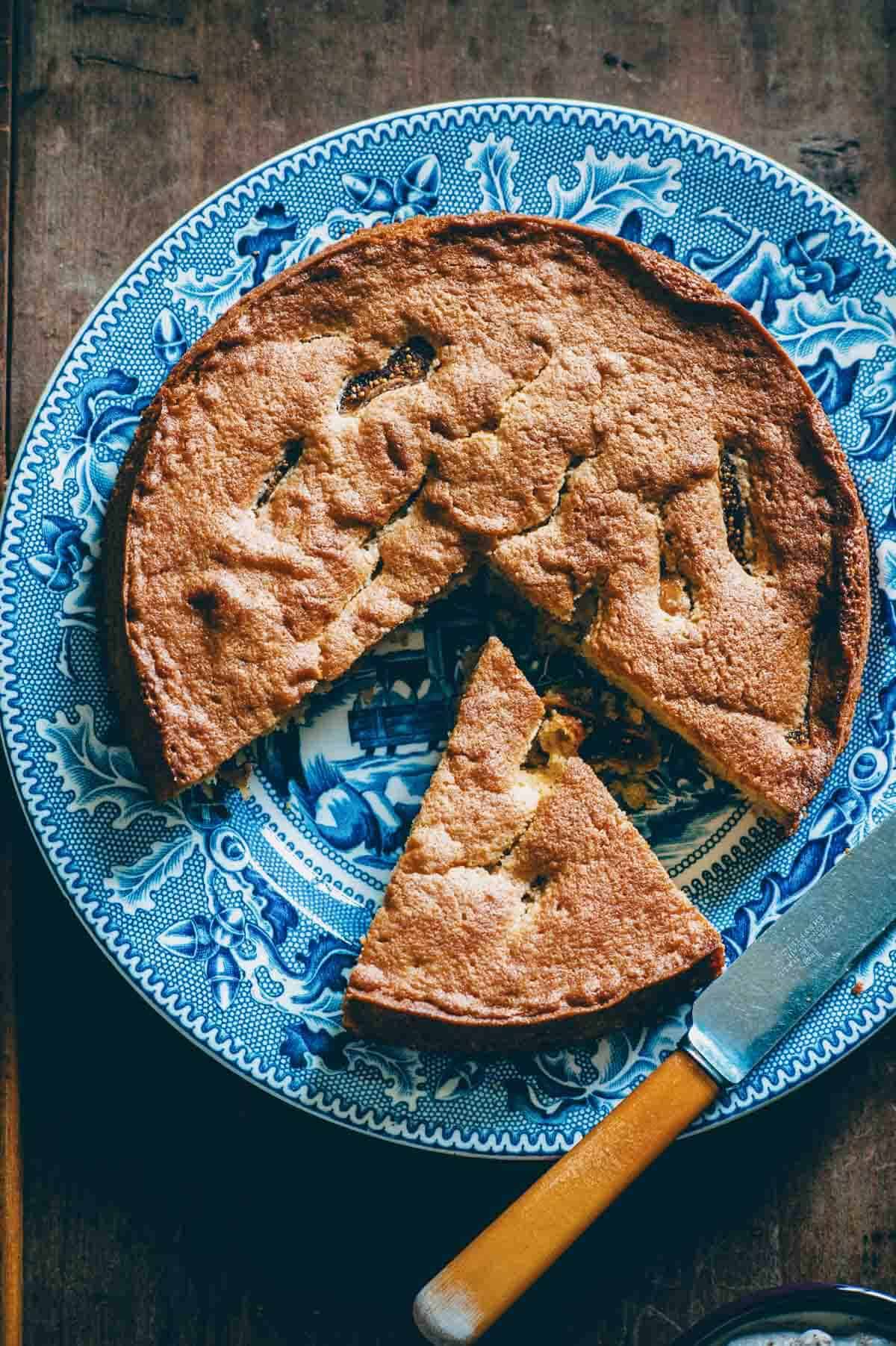 Whole dried fig and almond cake on blue plate.