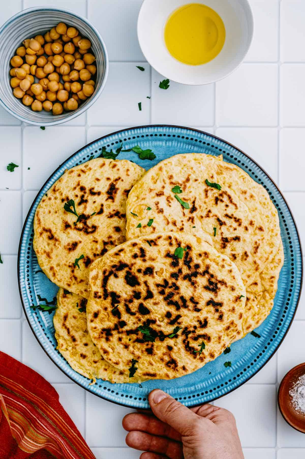 Stack of homemade chickpea flatbreads on a blue plate.