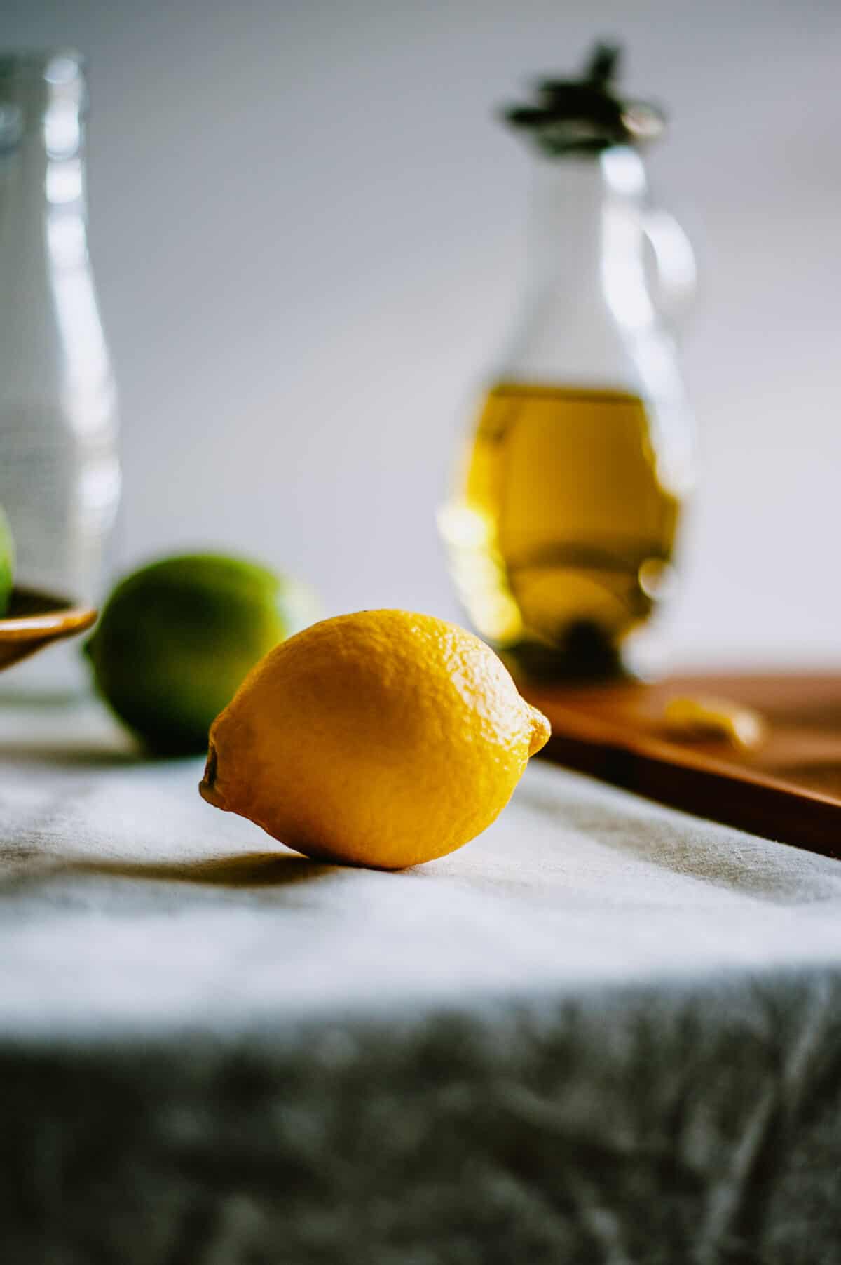 close up of lemon with olive oil bottle in the background.