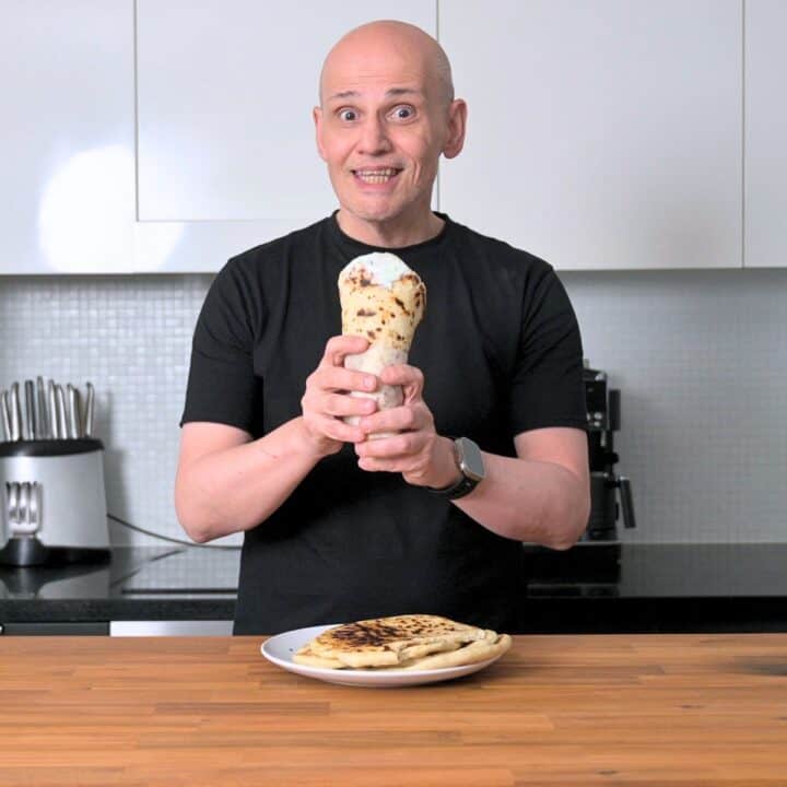 Peter, founder of Souvlaki For The Soul, holding a homemade pork souvlaki in his Melbourne kitchen.